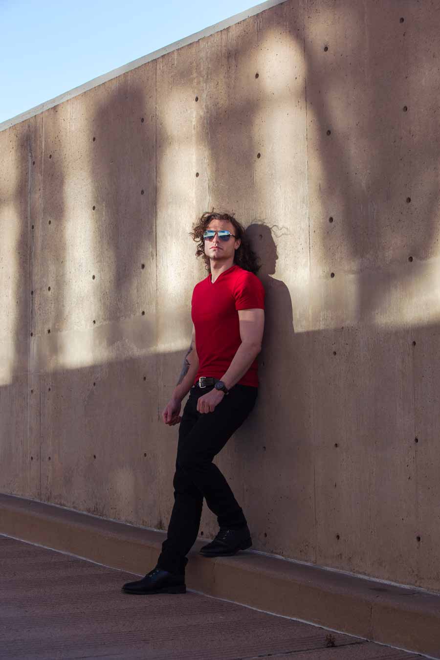 white male fashion photography model in denver in his twenties with shoulder length curly hair aviator sunglass and a red shirt